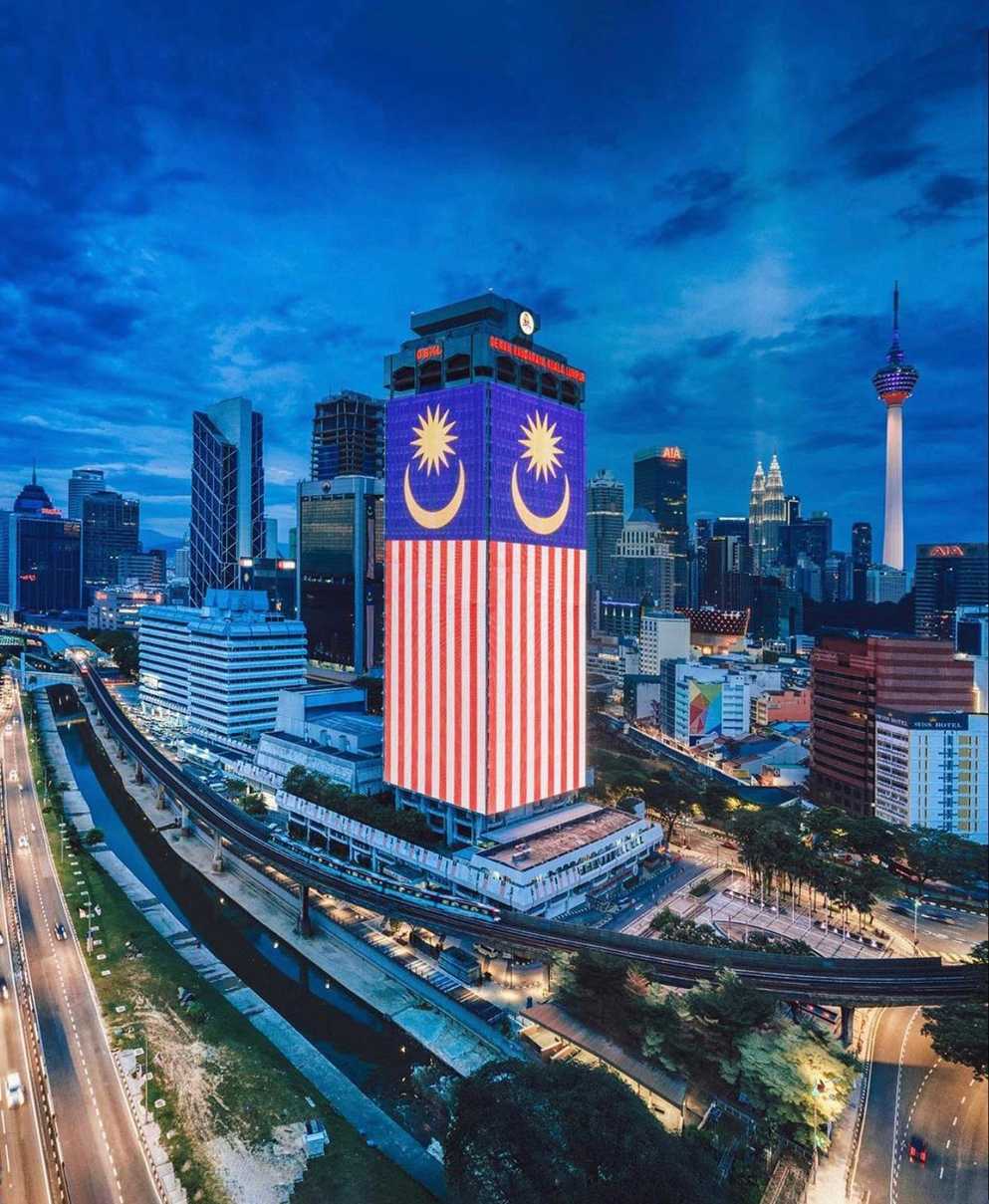 A scene where the lights at the building Dewan Bandaraya Kuala Lumpur illuminates a national flag