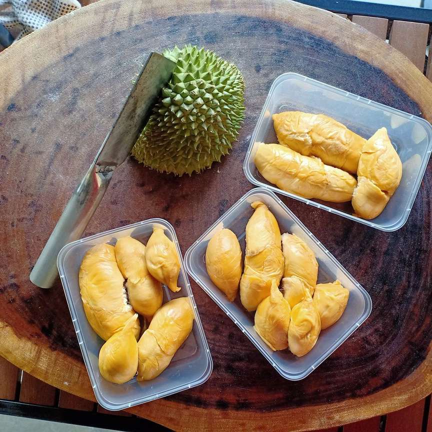durian opener on a durian shell with its fruit packed in transparent plastic boxes