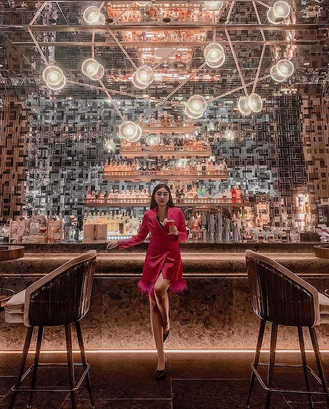 A lady in red dress standing in front of a cocktail bar counter