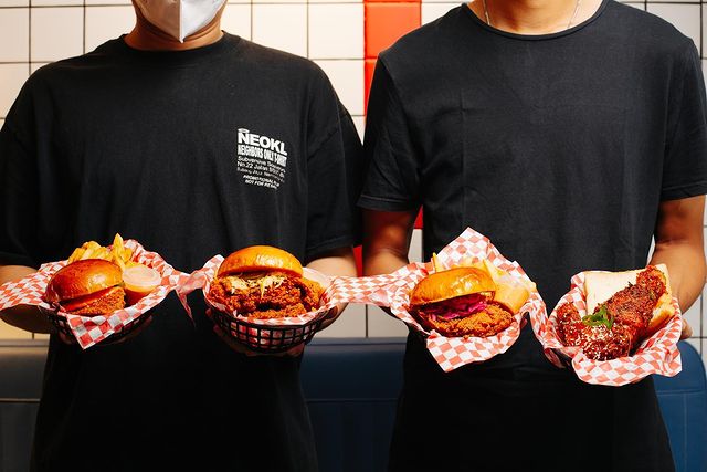 two guys holding two burgers each