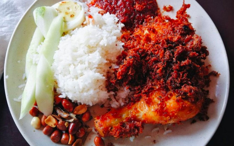cooked rice served with fried chicken drumstick, fried peanuts, anchovies, hard boiled egg and sliced cucumber