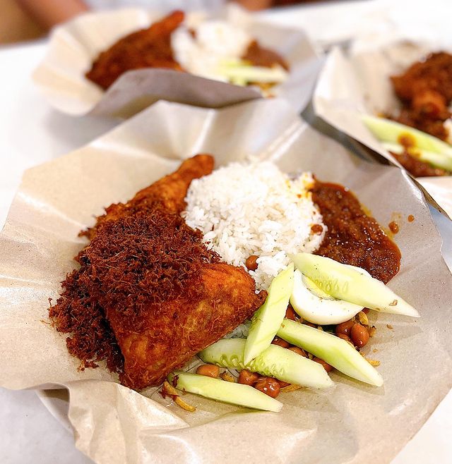 Nasi lemak with fried chicken and fresh cucumber wrapped in paper packaging