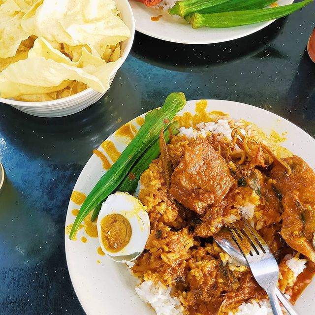 a plate of rice served with okra, chicken, salted duck egg and curry