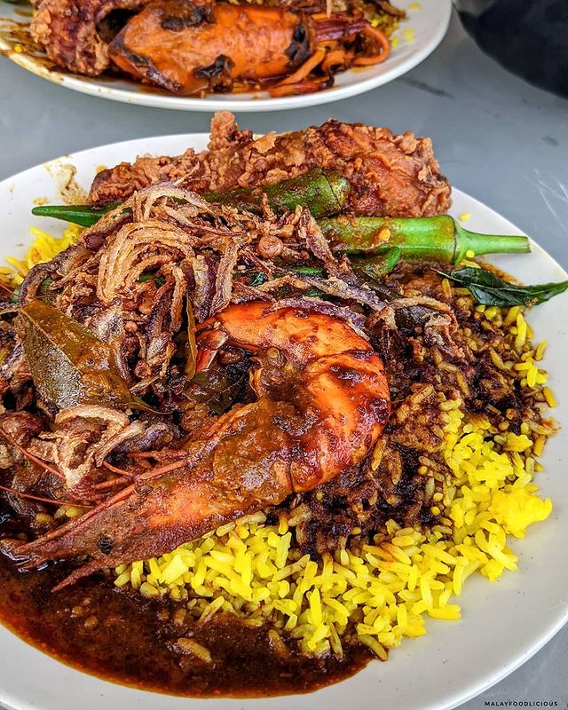 A plate of rice served with prawns, ladyfinger, chicken and curries