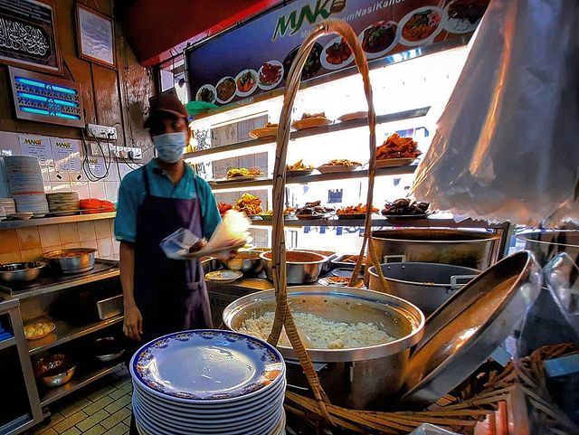 a restaurant crew preparing to serve a plate of rice with different dishes to choose from