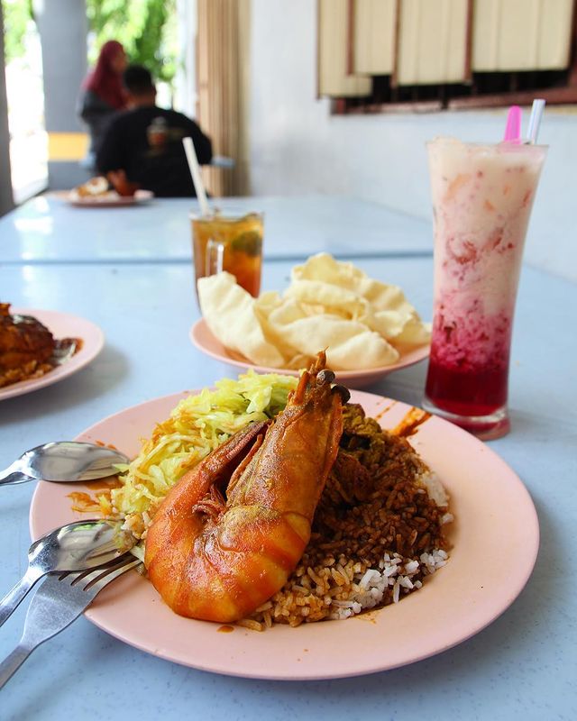a table in a restaurant with ice drinks and a plate of rice served with curry prawn and fried cabbage