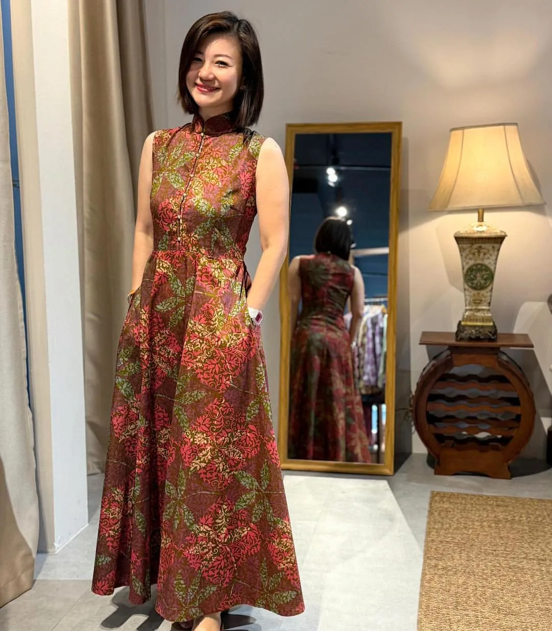 a model wearing a red batik designed dress with a mirror at her back