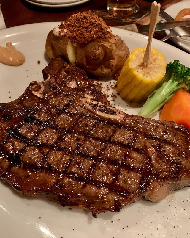 grilled steak served with potato, corn, broccoli and carrot