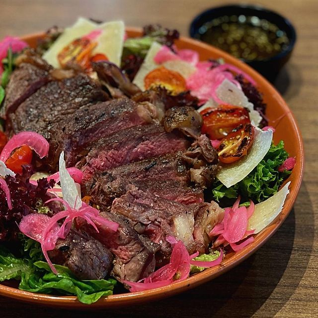 slices of grilled steak served with salads