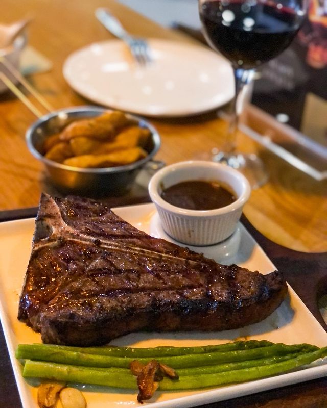 grilled t-bone steak served with asparagus, potato wedges and sauce