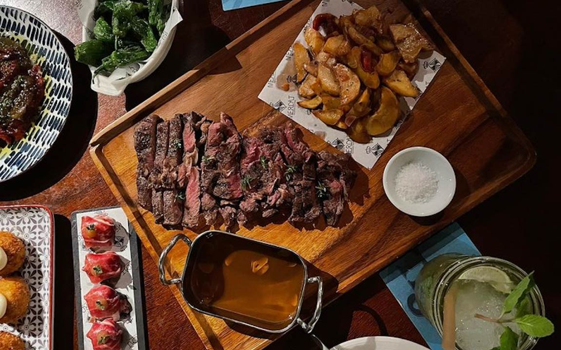 a tray of steak with side dishes