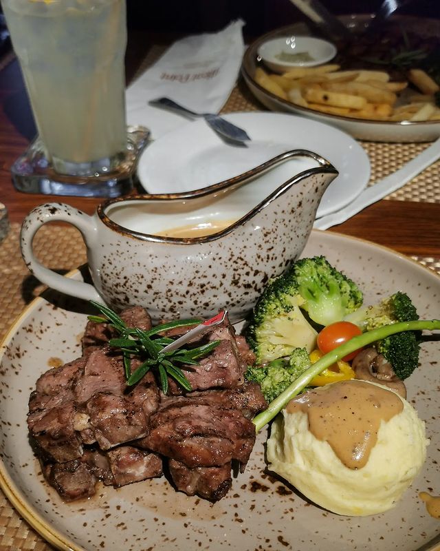 slices of grilled steak served with vegetables and mashed potatoes