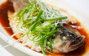 fish steamed on a plate garnished with spring onions