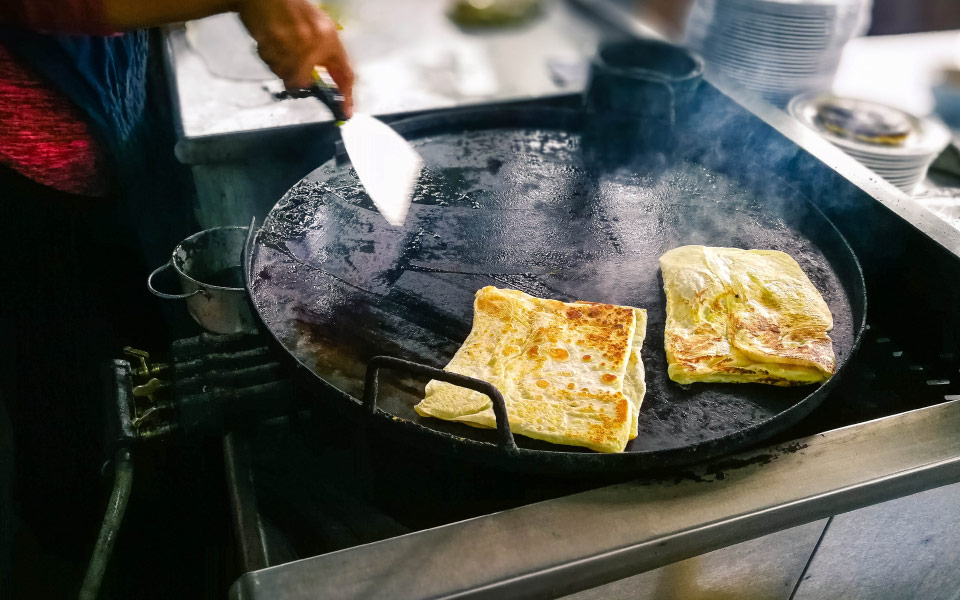 man cooking roti canai