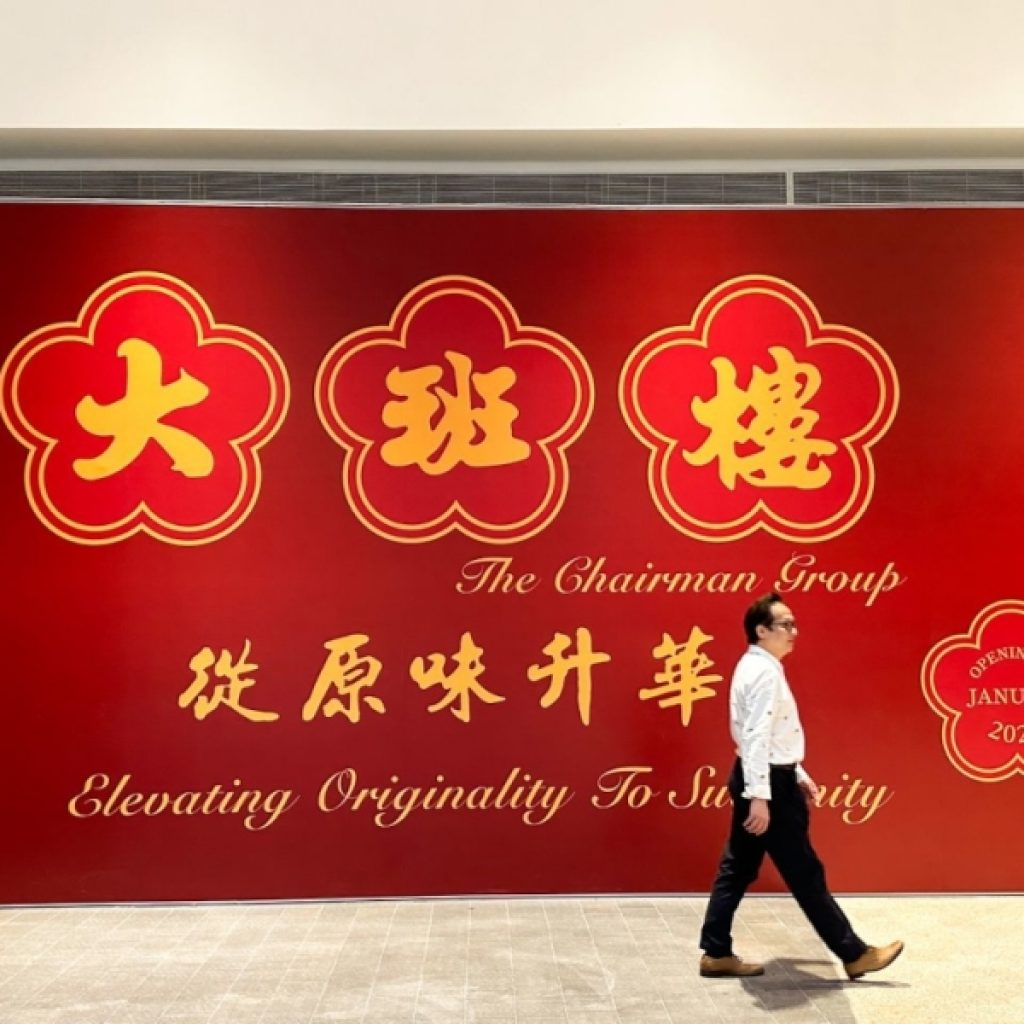 A man walking past a huge red signage of an announcement
