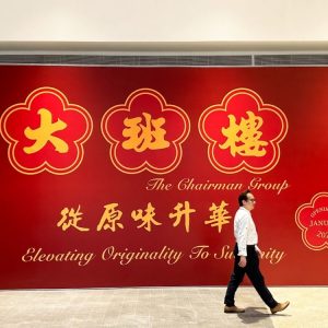 A man walking past a huge red signage of an announcement
