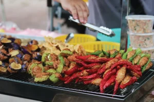 a hand holding a metal tongs in front of fried foods