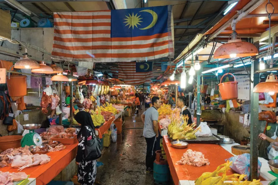 market selling fruits with a Malaysia flag hanging above