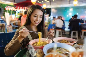 woman enjoying a bowl of noodles at a hawker centre