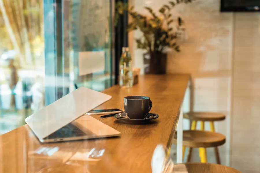 laptop, smartphone and coffee cup on a long table