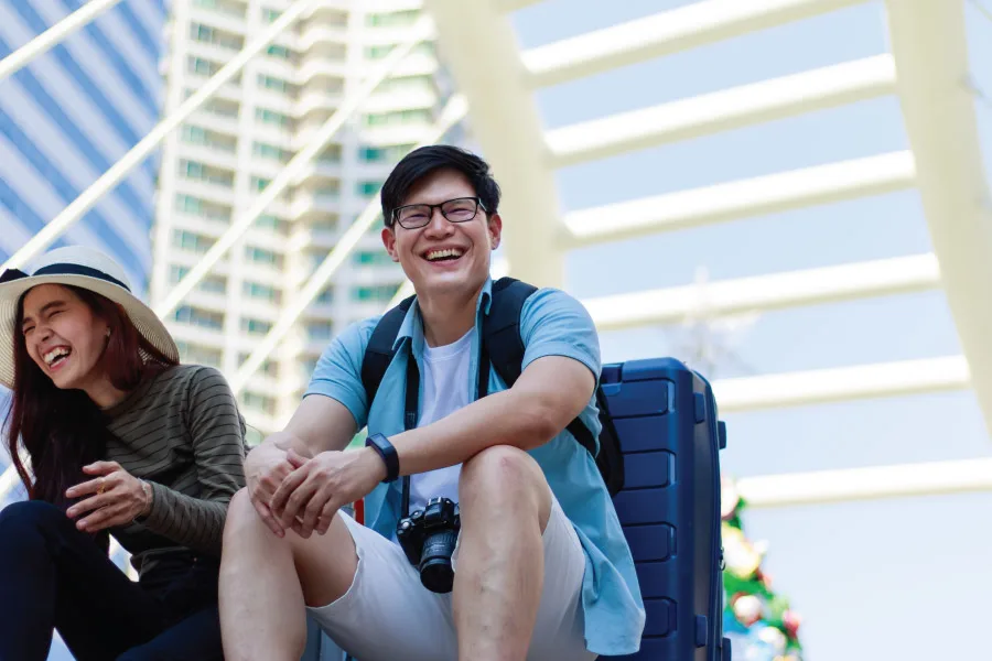 Two Asian sitting with a luggage in an urban city