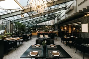black tables and chairs equipped with utensils in a restaurant