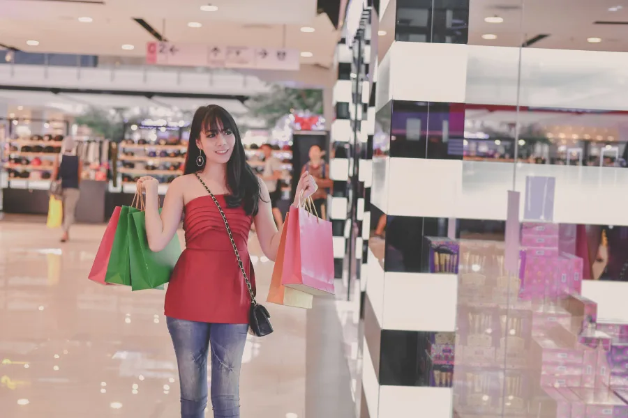 a woman holding shopping bags inside a modern shopping mall