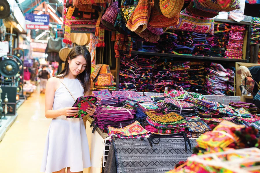 a woman standing by the stall and choosing a souvenir to buy