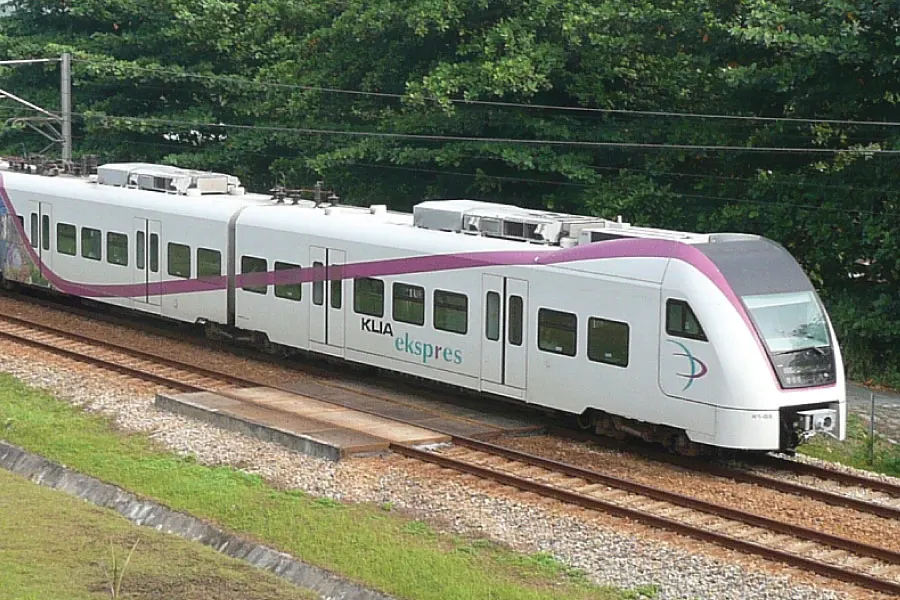a train on tracks passing by an area with trees