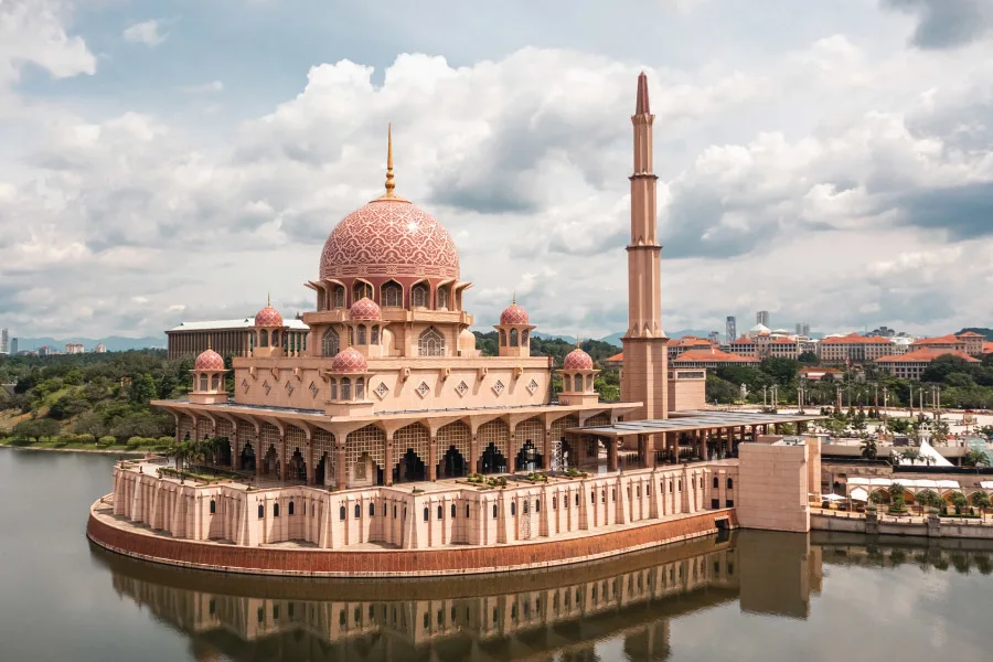 a pink coloured mosque floating by the lake