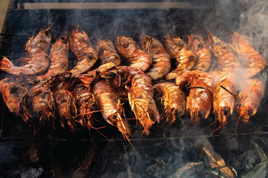 shrimps grilled in rows under hot charcoal heat