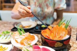 young woman dining at a restaurant served with sashimi