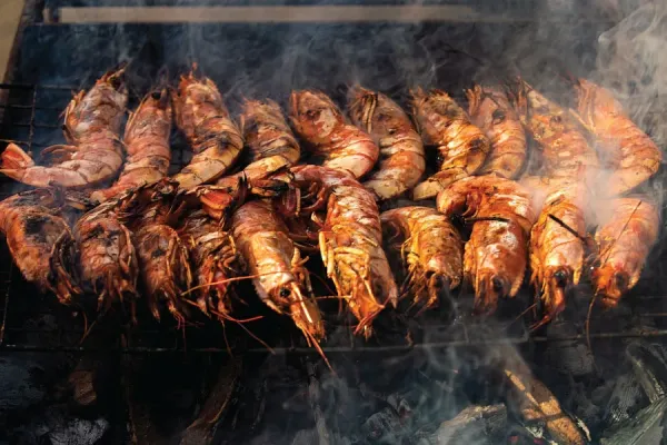 shrimps grilled in rows under hot charcoal heat