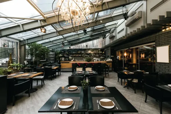 black tables and chairs equipped with utensils in a restaurant