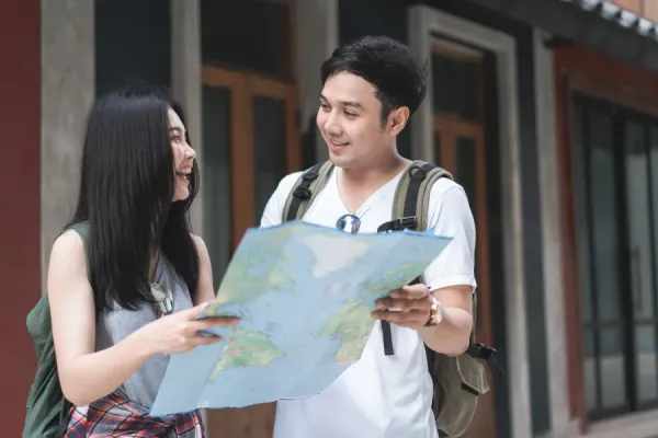 young tourists talking with each other while holding a map